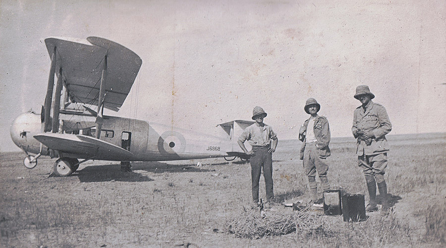 Cyril Ellen (centre) and two others standing with Vickers Vernon J6868 on a desert mud flat.